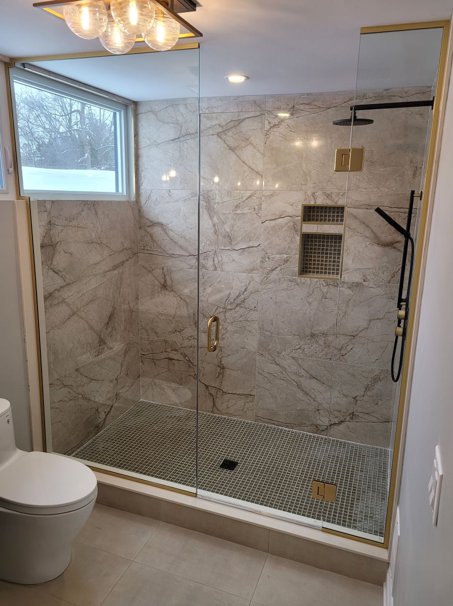 custom glass shower with floor to ceiling glass and satin brass hardware 