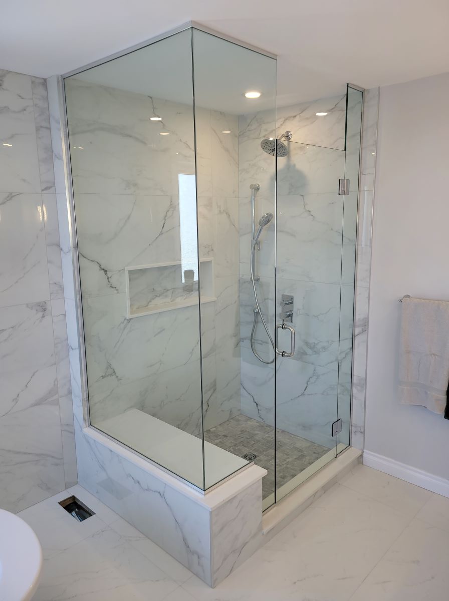 custom glass shower with floor to ceiling glass and chrome hardware with the glass notched over the bench 
