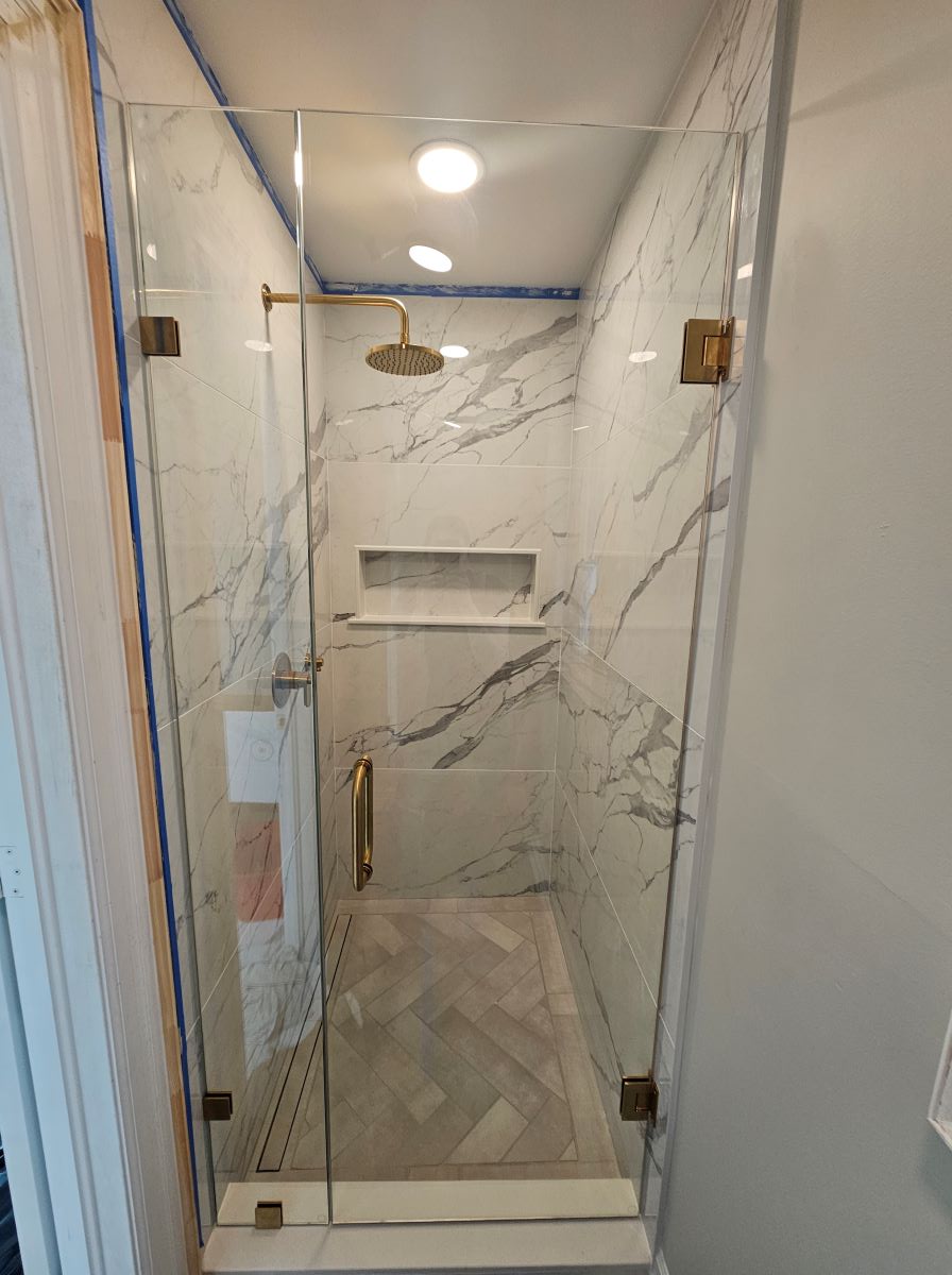 small frameless glass shower installed with satin brass glass clamps