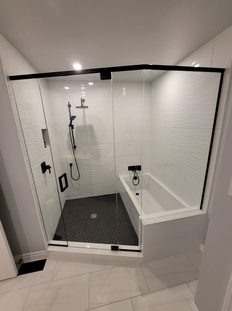 custom glass shower with the bath tub inside the shower. matte black hardware with a header and pivot door 