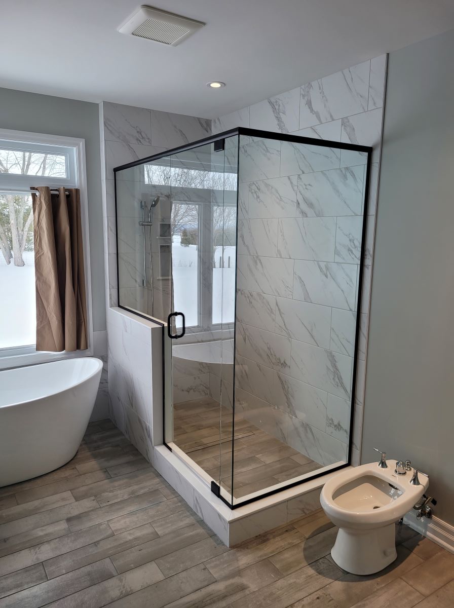 custom glass shower with matte black header and pivot door with the glass notched over the knee wall