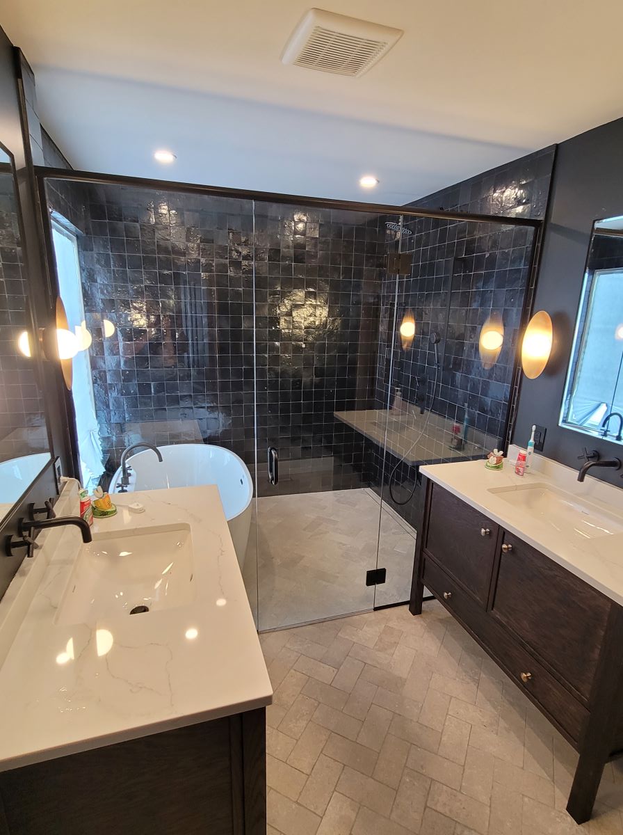 custom glass shower with glass hinged and header matte black hardware. custom design with bath tub inside the shower 