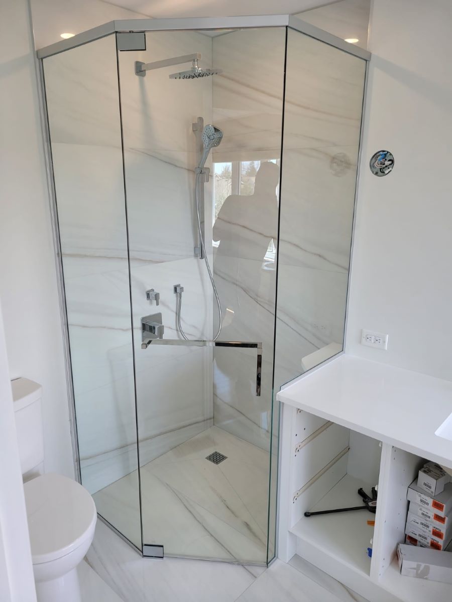 custom glass neo angle shower with the glass notched over the counter and square chrome hardware with a towel bar handle combo 