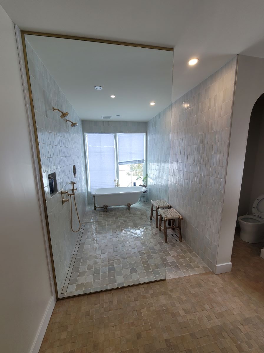 large glass panel with no door all the way the the ceiling with satin brass hardware