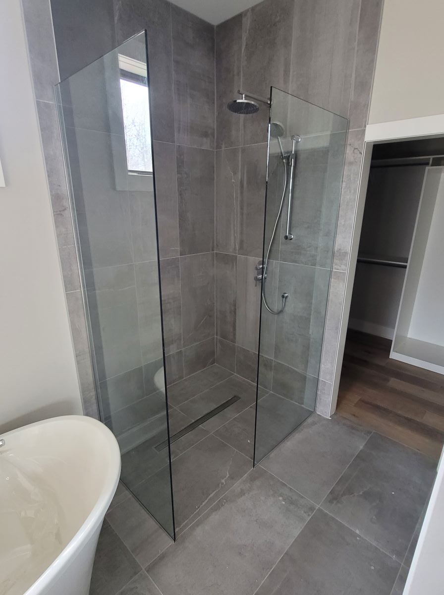 open concept glass shower with 2 glass panels and no door installed with chrome hardware