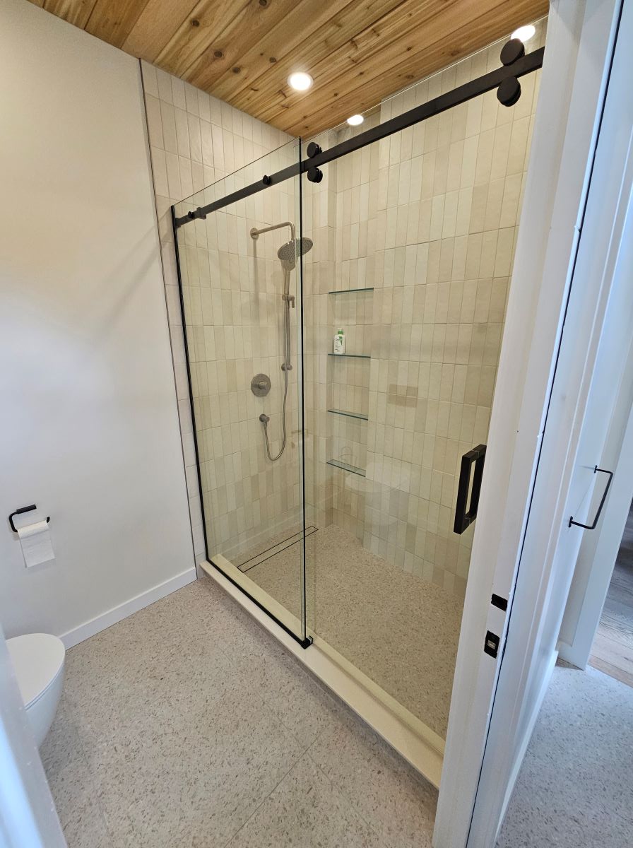 custom glass sliding door shower with matte black hardware and a square handle 