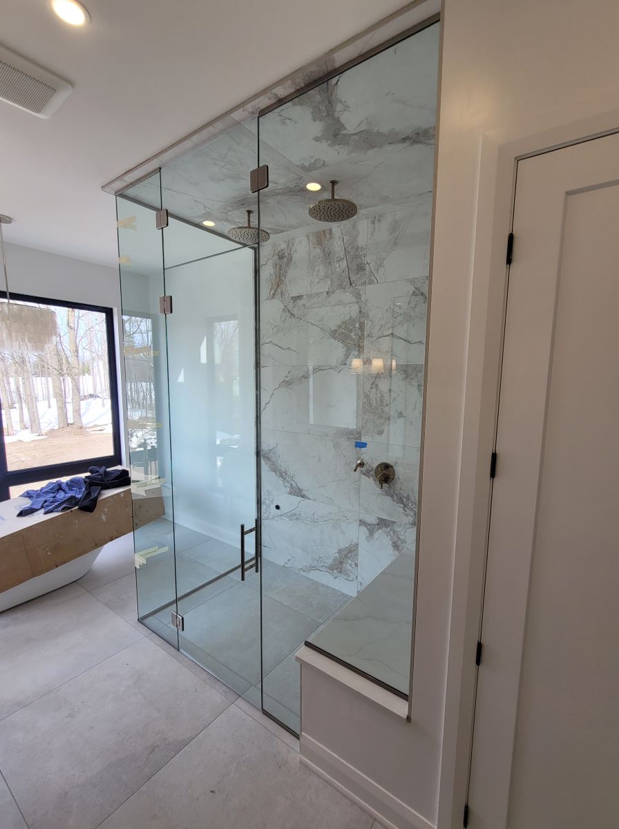 custom glass steam shower with glass notched over the bench and brushed nickle hardware and ladder pull handle 