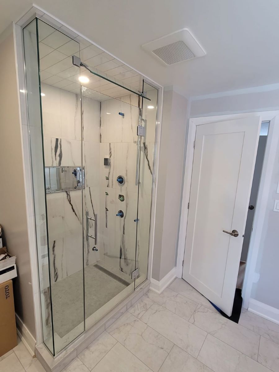 custom glass steam shower with a movable transom above the door and chrome hardware with a ladder pull handle 